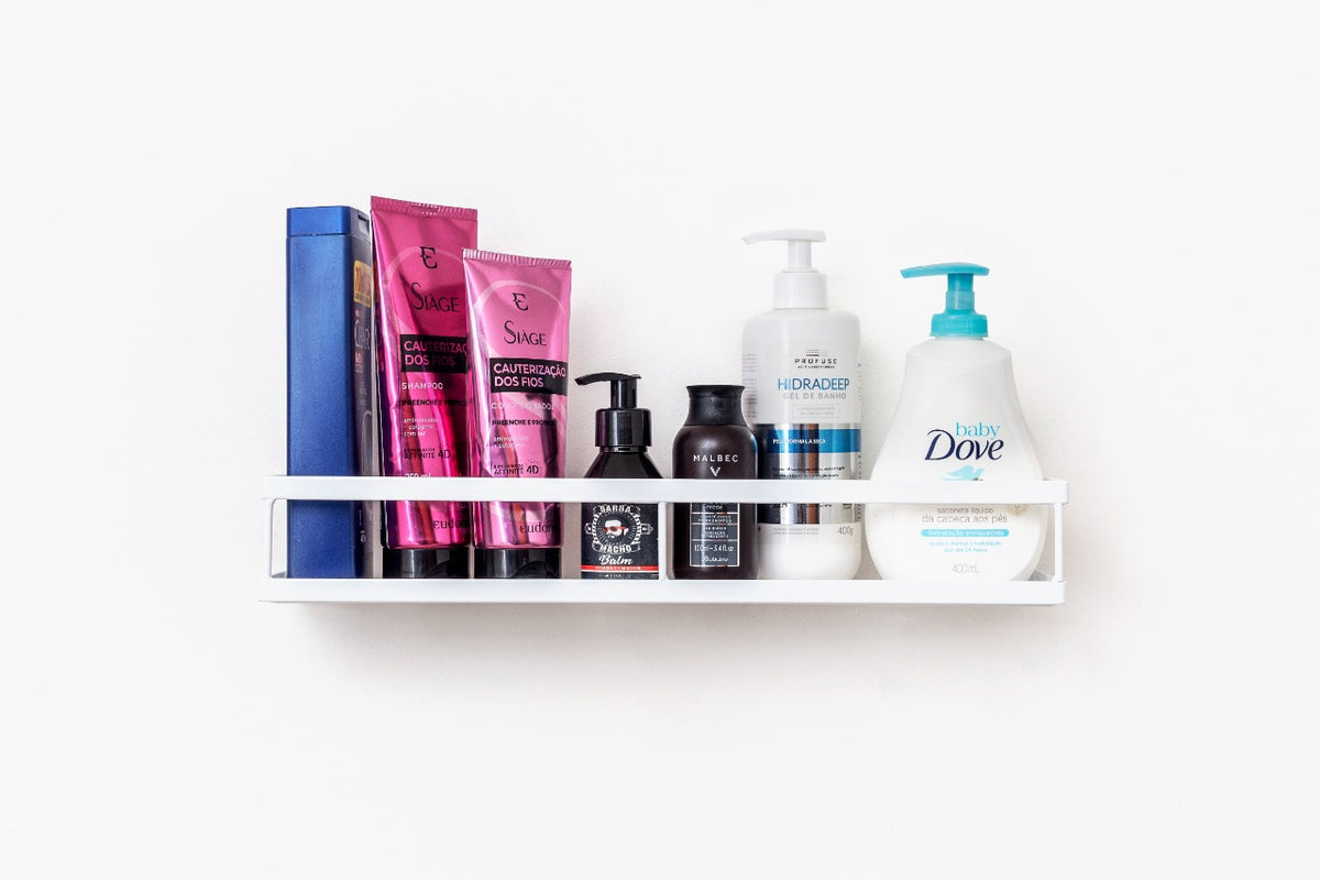 Produtos de cuidados pessoais organizados em prateleira branca, incluindo shampoos e géis