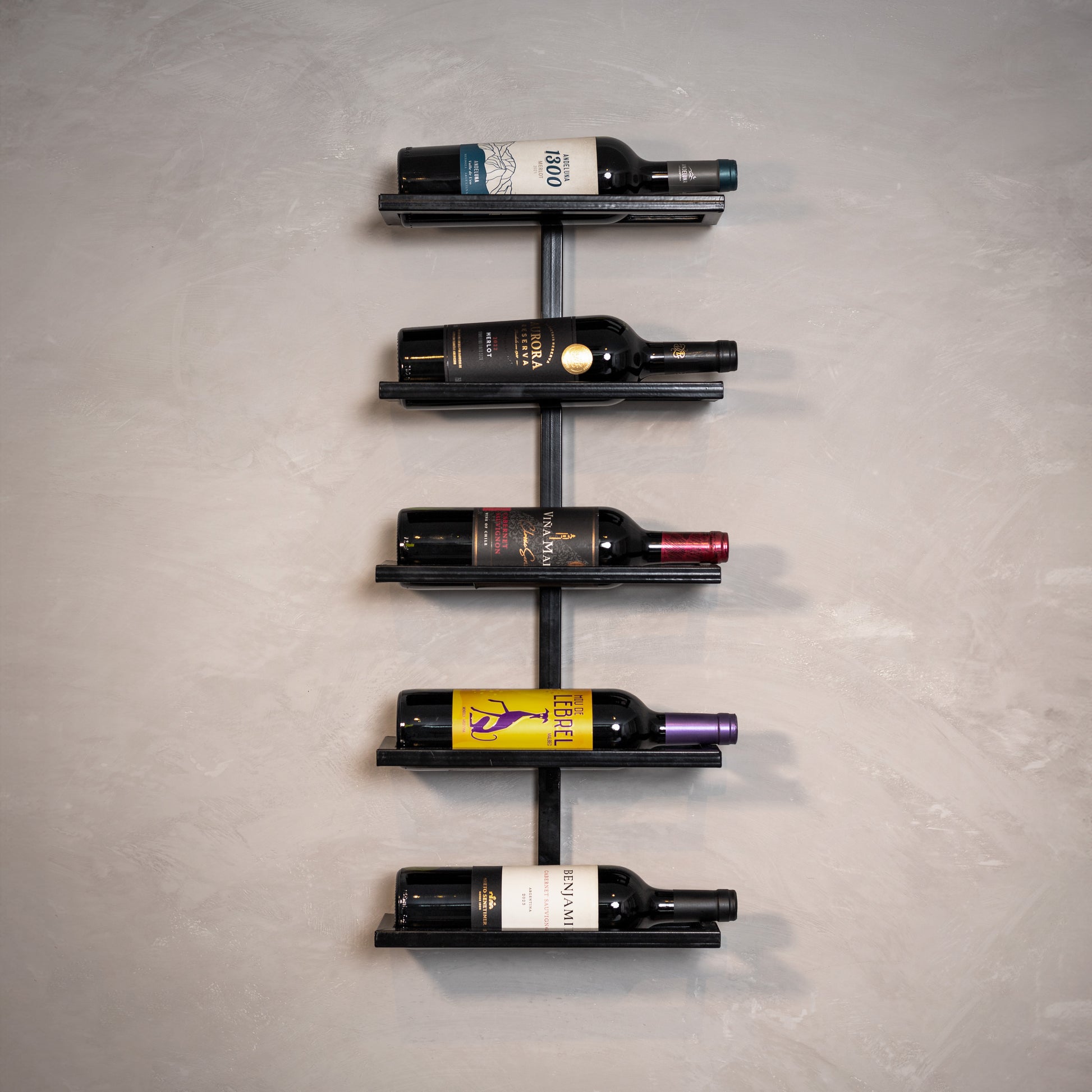 Estante de vinho moderna com garrafas coloridas em parede cinza, ideal para decoração sofisticada e organização.